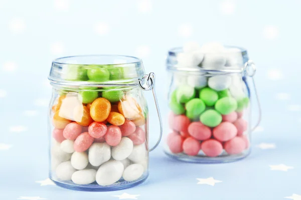 Mehrfarbige Bonbons in Glasgefäßen auf buntem Hintergrund — Stockfoto