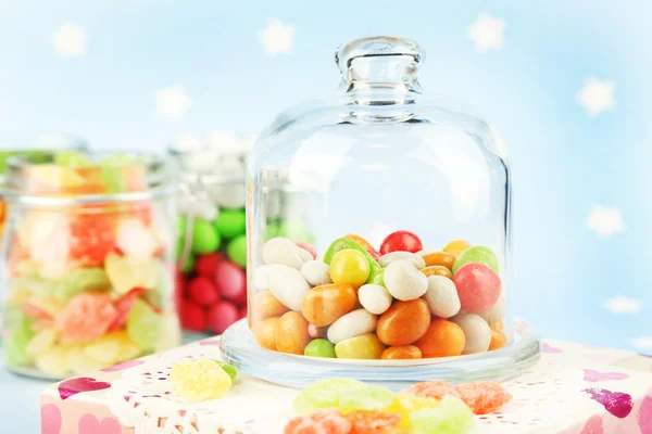 Doces multicoloridos em frascos de vidro sobre fundo colorido — Fotografia de Stock
