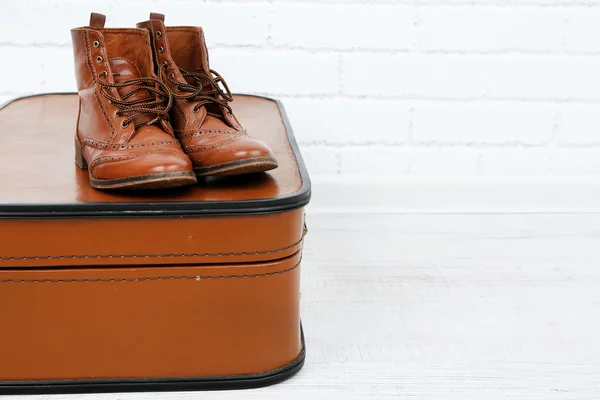 Vintage suitcase with male shoes on wooden floor and brick wall background — Stock Photo, Image