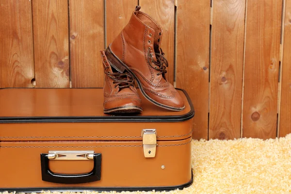 Retro-Koffer mit Männerschuhen auf Fellteppich und Hintergrund — Stockfoto