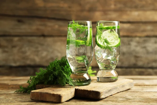 Vasos con agua fresca de pepino orgánico sobre mesa de madera —  Fotos de Stock