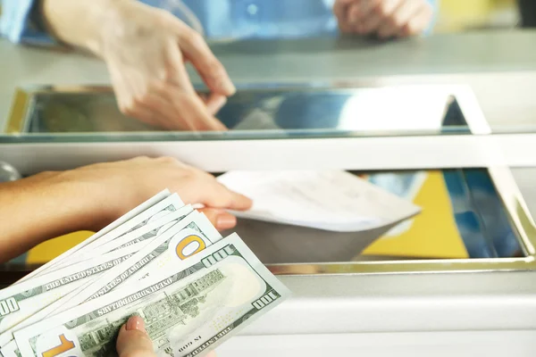 Vrouwelijke hand met geld in contanten departement venster. Munt uitwisseling concept — Stockfoto