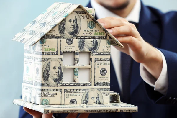 Model of house made of money in male hands on white background — Stock Photo, Image