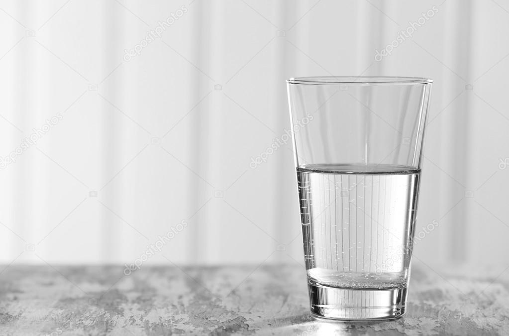 Glass of clean mineral water on old color wooden surface and planks background