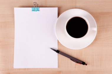 Fincan kahve fincan tabağı üzerinde kağıt ve kalem ahşap masa arka plan üzerinde levha ile