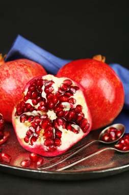 Koyu arka plan üzerinde metal plaka üzerinde sulu olgun nar