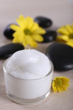 Çiçek ve spa taşlar ahşap arka plan üzerinde kozmetik krem