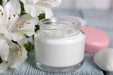 Çiçek ve spa taşlar ahşap arka plan üzerinde kozmetik krem