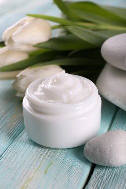 Çiçek ve spa taşlar ahşap arka plan üzerinde kozmetik krem