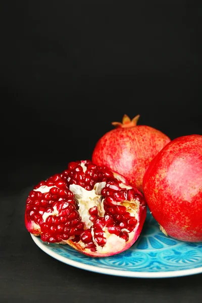 Juicy ripe pomegranates on wooden table, on dark background — Stock Photo, Image