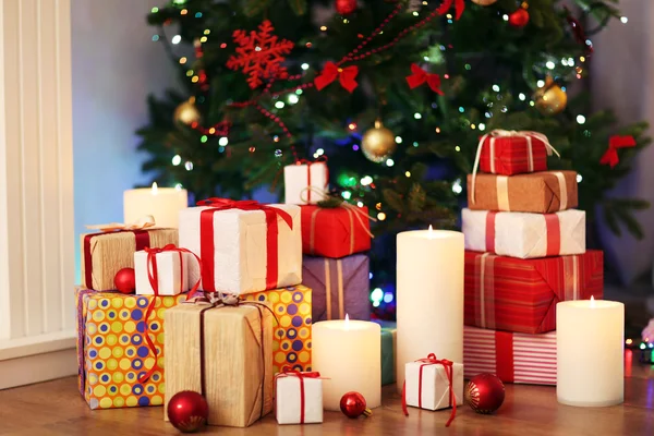 Stapel van huidige vakken onder kerstboom op houten vloer, binnenshuis — Stockfoto