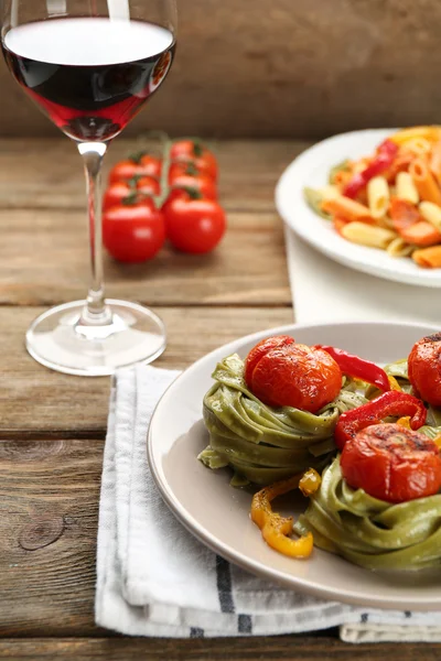 Zwei Arten von leckeren Nudeln mit Paprika, Karotten und Tomaten auf Holztischhintergrund — Stockfoto