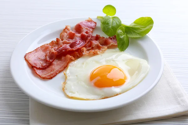 Bacon and eggs on color wooden table background — Stock Photo, Image