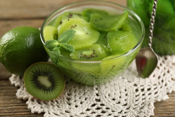 Tasty kiwi jam in glass bowl and jar on wooden background — Stock Photo, Image