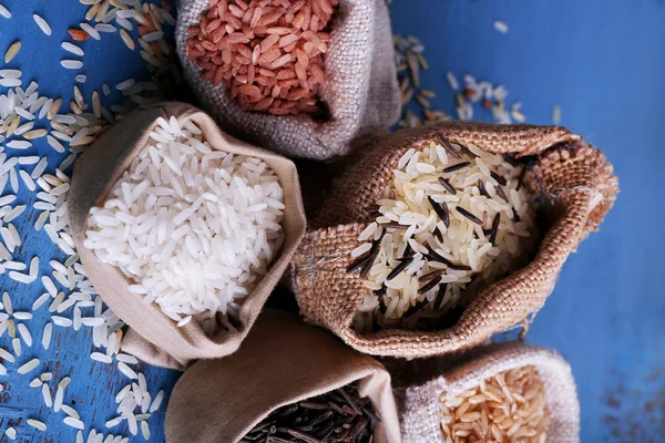 Diferentes tipos de arroz en sacos sobre fondo de madera — Foto de Stock