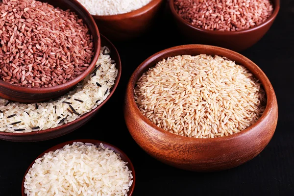 Diferentes tipos de arroz em tigelas em fundo de madeira — Fotografia de Stock