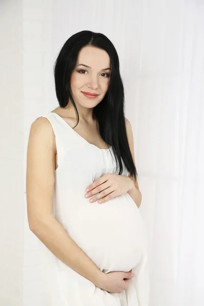 Jeune femme enceinte sur fond clair — Photo