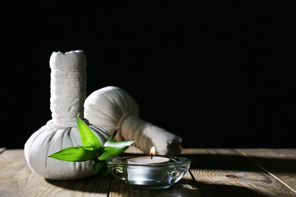 Beautiful composition with massage bags and candle on table on dark background — Stock Photo, Image