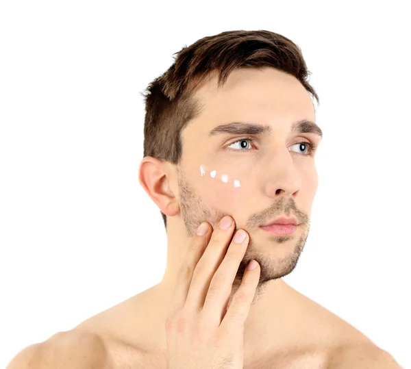 Hombre joven guapo aplicando loción crema en la cara aislada en blanco —  Fotos de Stock