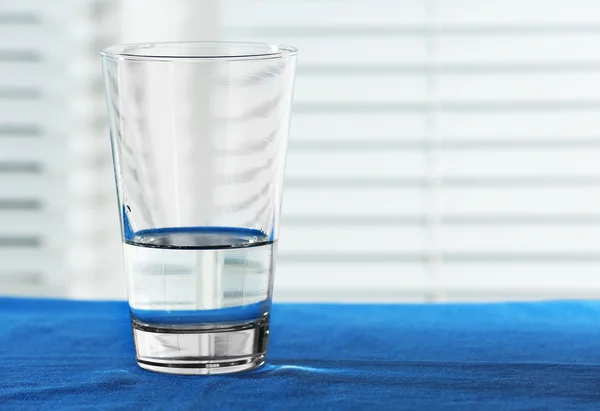 Szklanka wody na stole na jasnym tle — Zdjęcie stockowe