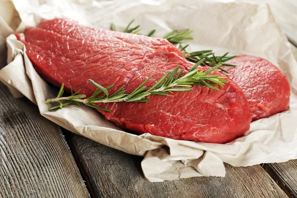 木製の背景の紙にローズマリーの牛肉ステーキ — ストック写真