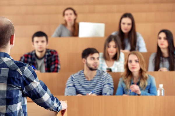 Groep van studenten in de klas zitten en luisteren leraar — Stockfoto