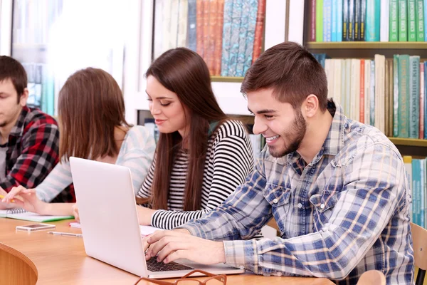 Group of students sitting at table in library — Stock Photo, Image