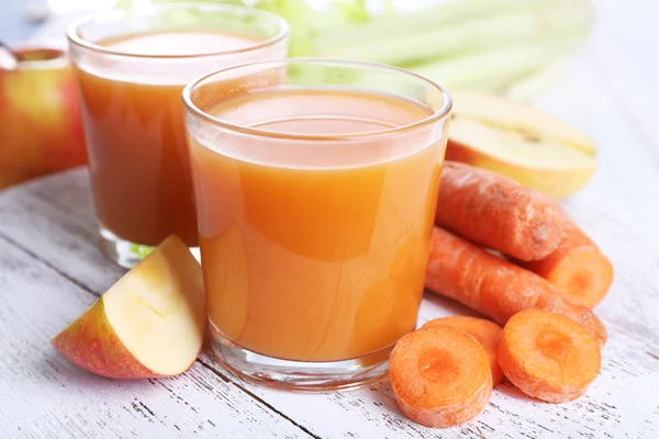 Verres de jus de pomme et de carotte sur table en bois close up — Photo