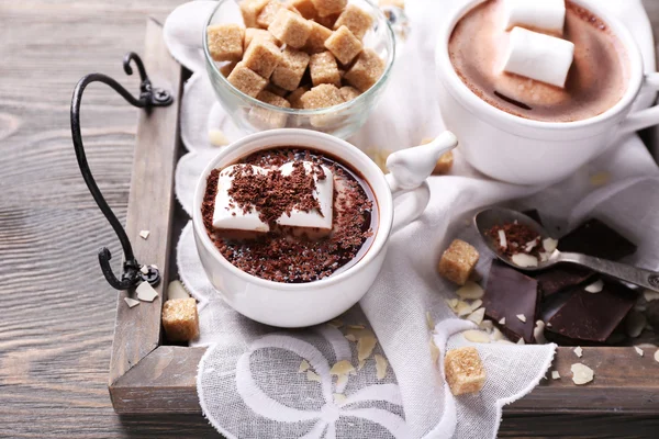 Cioccolata calda con marshmallow in tazza, su vassoio, su sfondo di legno a colori — Foto Stock