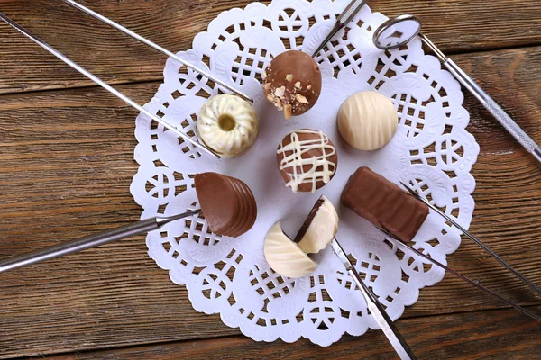 Tandläkare verktyg med godis på lacy servett på trä bakgrund — Stockfoto