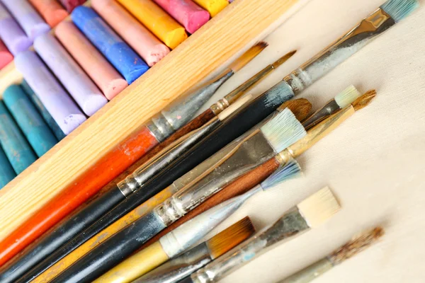 Paintbrushes with colorful chalk pastels in box on fabric background — Stock Photo, Image