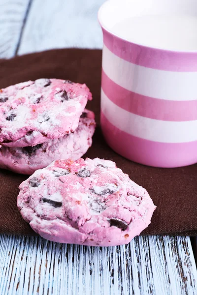 Biscotti rosa e tazza con latte in tavola primo piano — Foto Stock