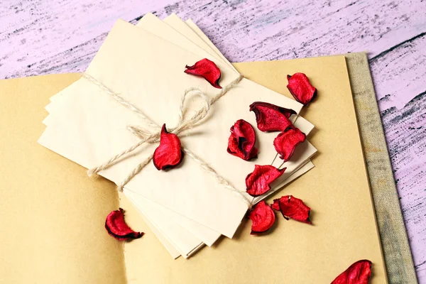 Surat cinta dan kelopak mawar pada latar belakang kayu — Stok Foto