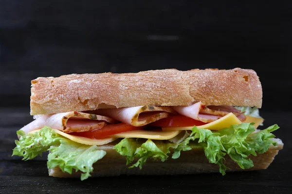 Fresh and tasty sandwich with ham and vegetables on wooden background — Stock Photo, Image