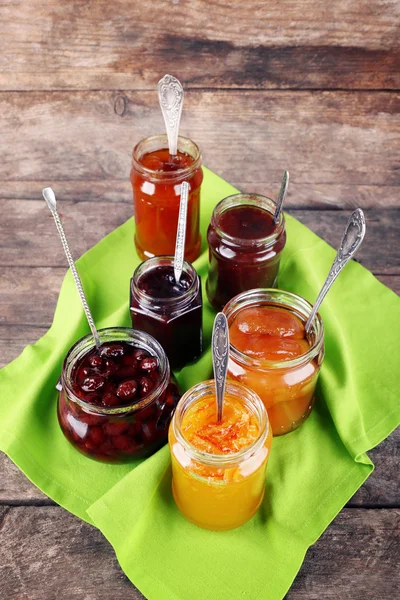 Gläser leckere Marmelade mit Serviette auf Holzgrund — Stockfoto