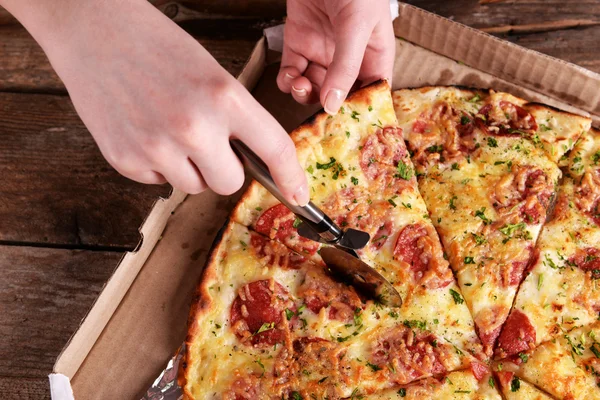 Girl cut pizza on table close up — Stock Photo, Image