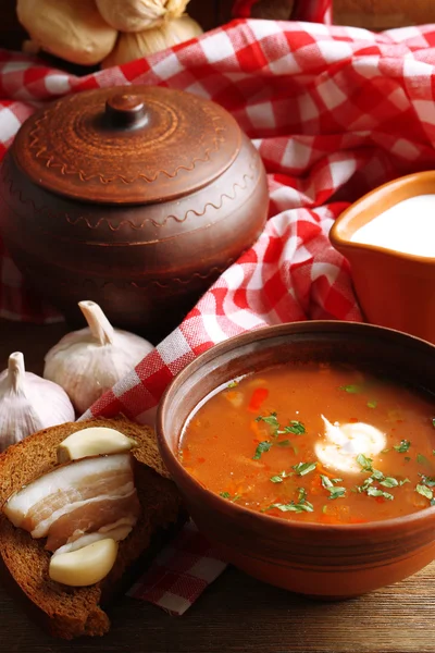 Ukrainian beetroot soup - borscht in bowl and pot, on napkin, on wooden background — Stock Photo, Image