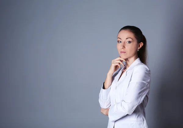 Portrét mladé ženy na šedém pozadí — Stock fotografie