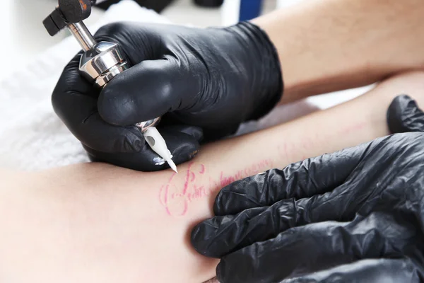 Tattooer visar processen att göra tatuering, närbild — Stockfoto