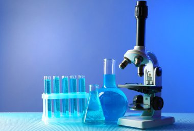 Mikroskop ve masaya renk arka plan üzerinde test tüpleri