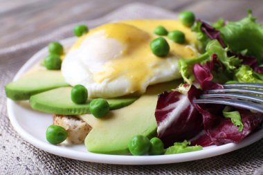 Yumurta Benedict ve avokado masada plaka üzerinde yakından ile tost