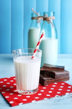 Cam ve süt noktalar peçete ve renk ahşap plakalar zemin üzerine çikolata parçaları ile şişe