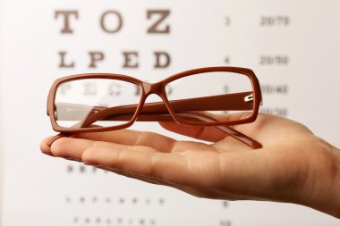 Eye glasses on eyesight test chart background clipart