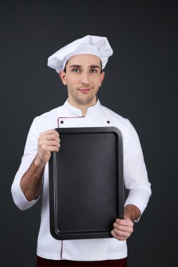 Şef koyu arka plan üzerinde elinde fırın tava ile portresi