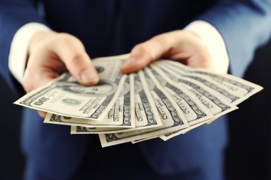 Koyu arka plan üzerinde para veren işadamı