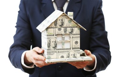 Beyaz arka plan üzerinde izole erkek elinde para yapılmış ev modeli