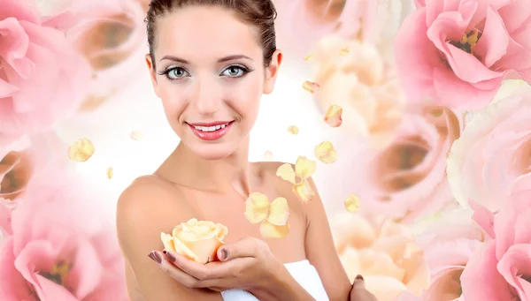 Красива молода жінка тримає кремову троянду на рожевому квітковому тлі — стокове фото