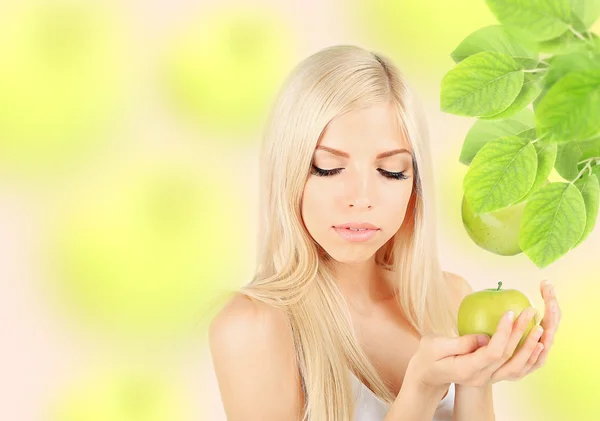 Hermosa joven con manzana verde sobre fondo natural — Foto de Stock