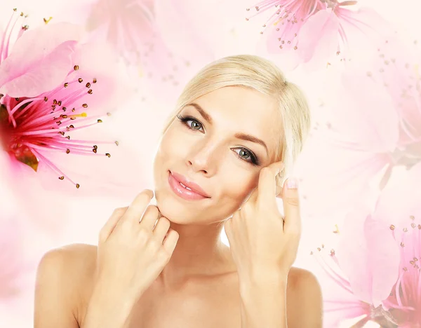 Schöne junge Frau auf Kirschblütenhintergrund — Stockfoto