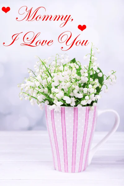 Belles fleurs en tasse sur table sur fond clair, Fête des Mères concept — Photo